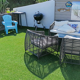 Salon de jardin sur un balcon avec gazon synthétique court