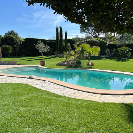 Aménagement d'un grand jardin avec piscine arrondie et pelouse synthétique