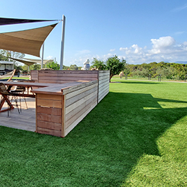 Terrasse en bois avec voile d'ombrage dans un jardin en gazon artificiel