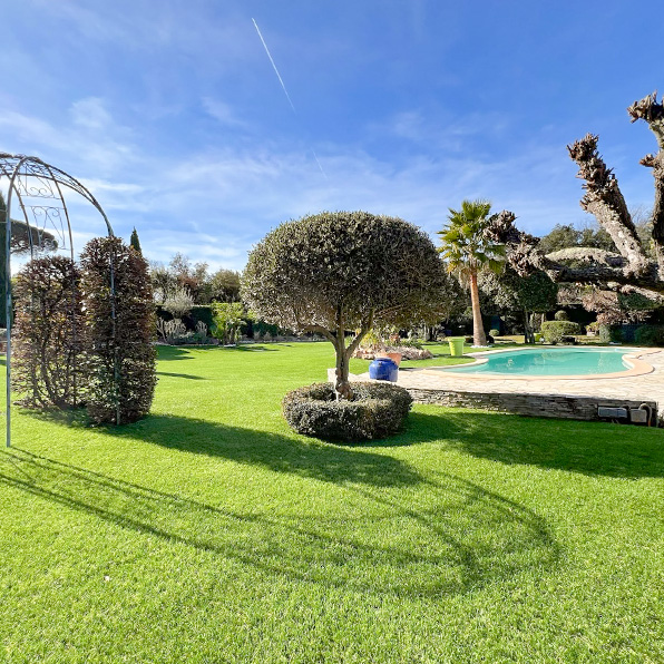 jardin aménagé avec gazon synthétique, piscine et tonnelle décorative