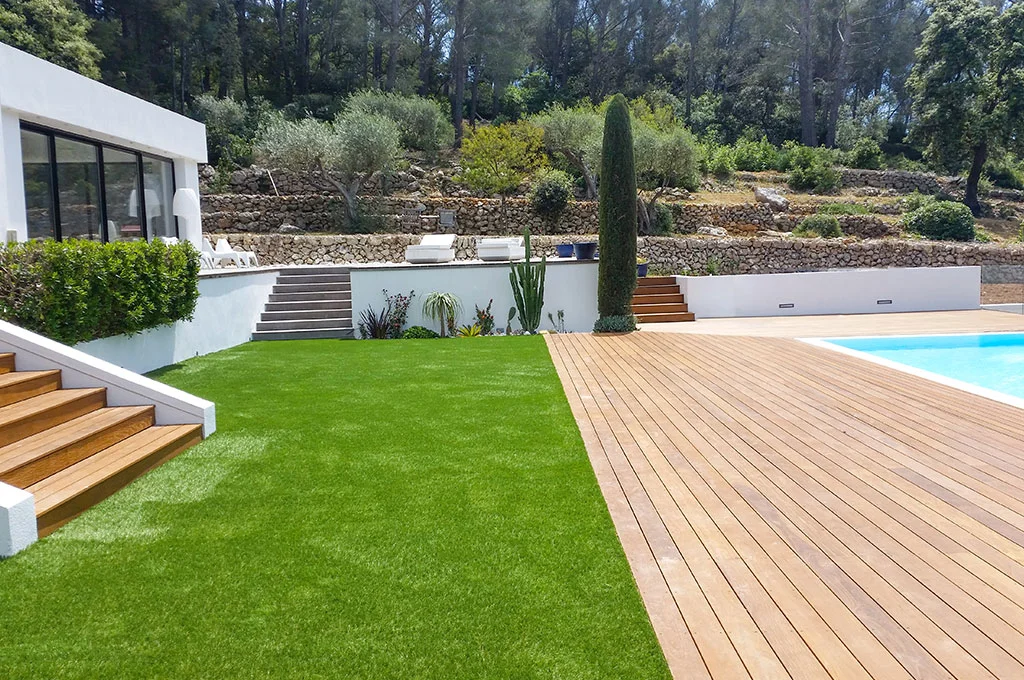 Réalisation d'un contour de piscine en gazon synthétique et plage en bois