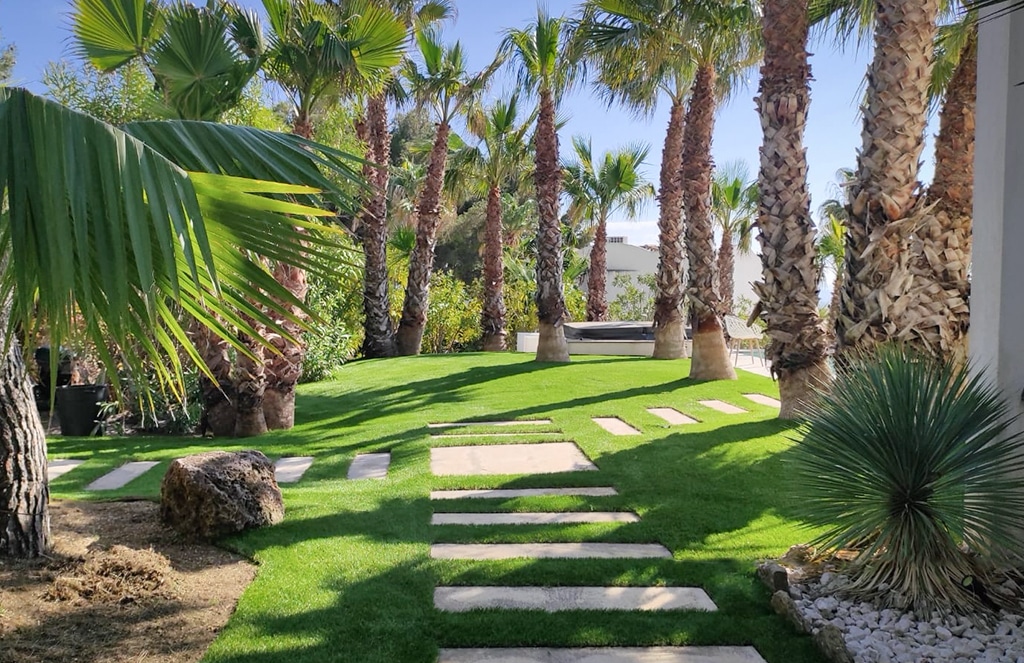 Jardin avec palmiers et découpe de dalles en gazon synthétique Luxe 50