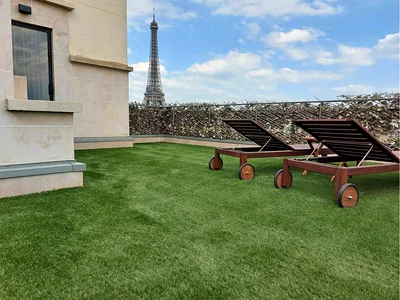 Achat et pose de gazon synthétique à Paris 2 Gazon synthétique découpé le long d'une façade en pierre sur un toit-terrasse parisien