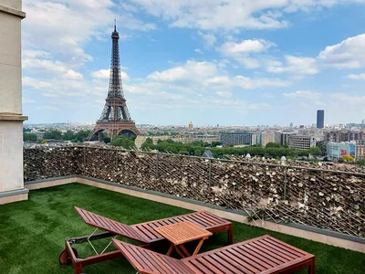 Achat et pose de gazon synthétique à Paris 3 Toit-terrasse parisien en gazon synthétique avec transats, vue sur la tour Eiffel