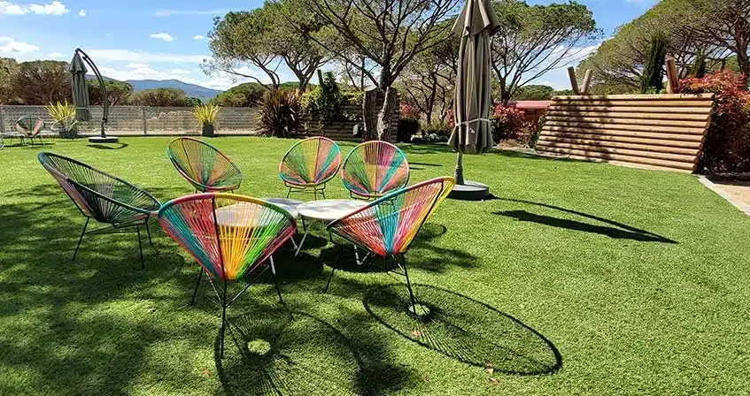 jardin avec du gazon synthétique et des chaises de jardin multicolores avec un parasol