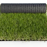 Échantillon de gazon artificiel Luxe 50 mm en rouleau vu de face avec rouleau en arrière plan